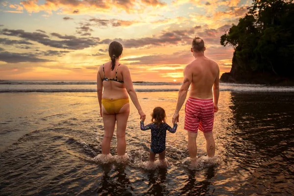 Οικογένεια στην παραλία έννοια, Καυκάσιος οικογένεια παίζει και μεταφέρουν την κόρη του στην τροπική παραλία στο ηλιοβασίλεμα. — Φωτογραφία Αρχείου