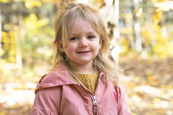 Little child girl in autumn park walking lonely — Stockfoto