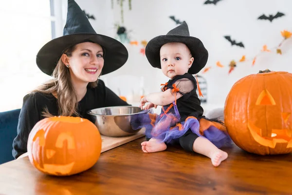Мать и дочка на кухонном столе, готовые к Хэллоуину с тыквой — стоковое фото