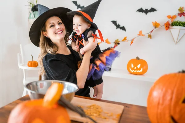 Rodina matka a dcera na kuchyňském stole připravena na Halloween s dýní — Stock fotografie