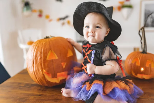 Красивая девочка в костюме ведьмы Хэллоуин на домашнем кухонном столе — стоковое фото