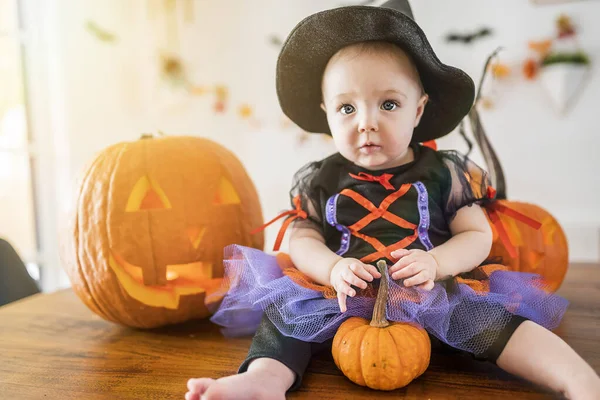 Beautiful baby girl in witch halloween costume at home kitchen table — Stock Photo, Image