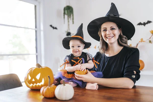 Rodina matka a dcera na kuchyňském stole připravena na Halloween s dýní — Stock fotografie