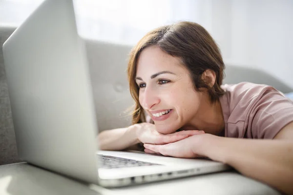 Vrouw ontspannen thuis op bank, genieten van vrije tijd met laptop op de bank — Stockfoto