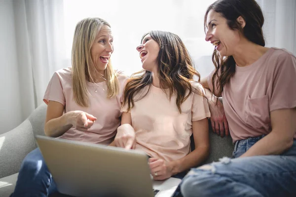 Glimlachen beste meisje vrienden blond en brunette zitten op de bank met laptop — Stockfoto