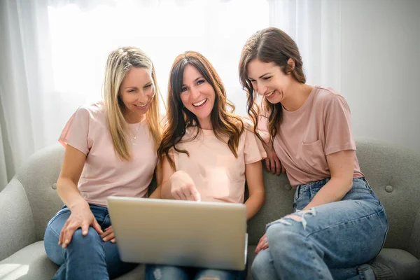 Glimlachen beste meisje vrienden blond en brunette zitten op de bank met laptop — Stockfoto