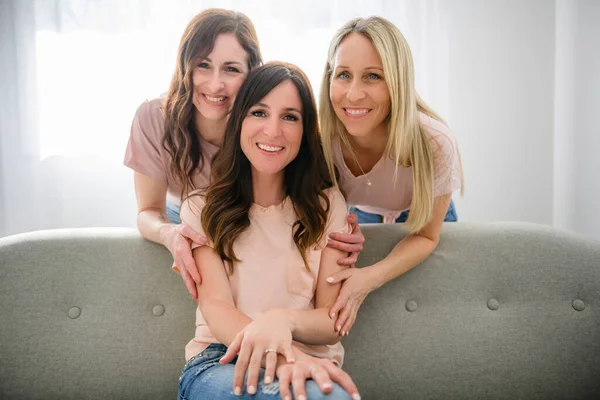 Smiling best girl friends blond and brunette sit on sofa — Stok fotoğraf