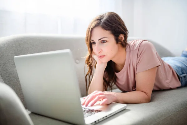 Vrouw ontspannen thuis op bank, genieten van vrije tijd met laptop op de bank — Stockfoto