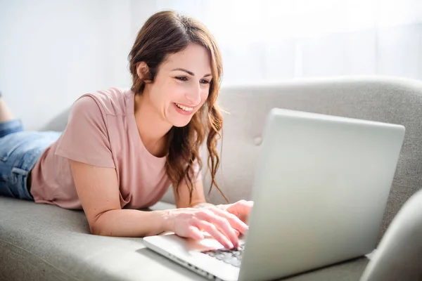 Vrouw ontspannen thuis op bank, genieten van vrije tijd met laptop op de bank — Stockfoto