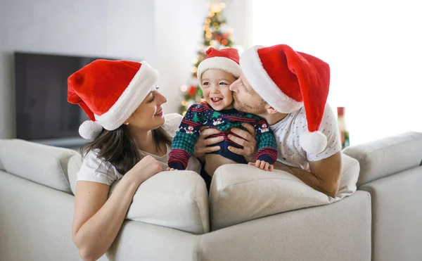 Família feliz sentado no sofá com sua menina no tempo de Natal — Fotografia de Stock