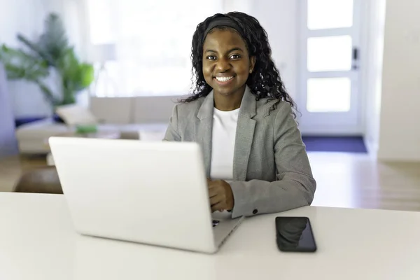 Portrait of a beautiful young woman with laptop and cellphone at home — Stock Photo, Image