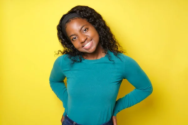 Cheerful African American female with pleasant smile over yellow background — Stock fotografie