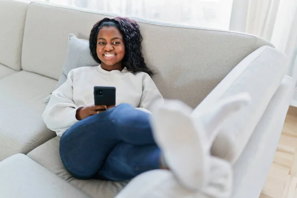 Portrait of a young woman using mobile phone on the sofa — Stockfoto