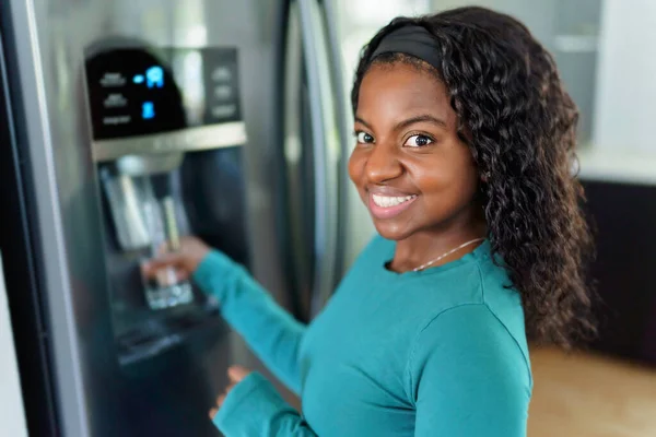 Mujer joven en frente del refrigerador en la cocina — Foto de Stock