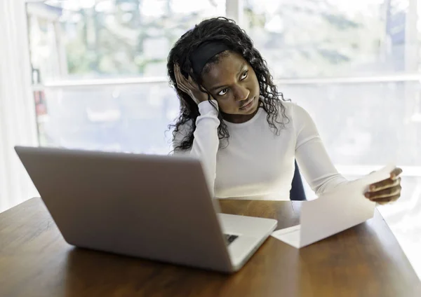 Portrait of a young business woman with laptop working on the kitchen table look sad because of bill to pay — Photo