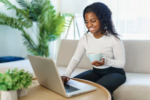 Portrait d'une belle jeune femme avec ordinateur portable assis sur le canapé — Photo