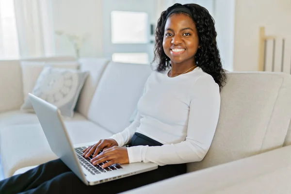 Πορτρέτο μιας όμορφης νεαρής γυναίκας με φορητό υπολογιστή κάθεται στον καναπέ — Φωτογραφία Αρχείου