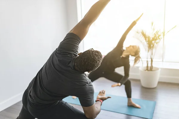 Personal trainer fazendo ioga pose em estúdio ensolarado com o cliente — Fotografia de Stock
