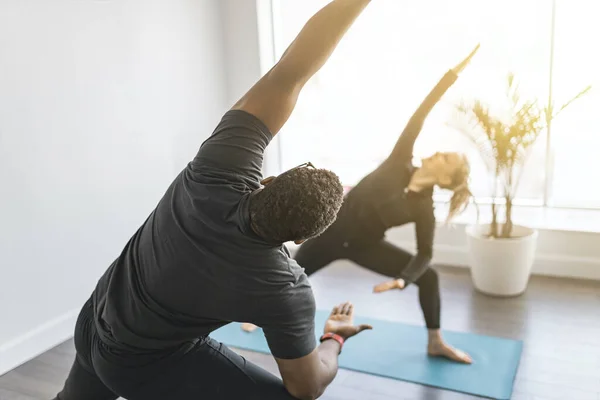 Personal trainer doing yoga pose in sunny studio with client — стоковое фото