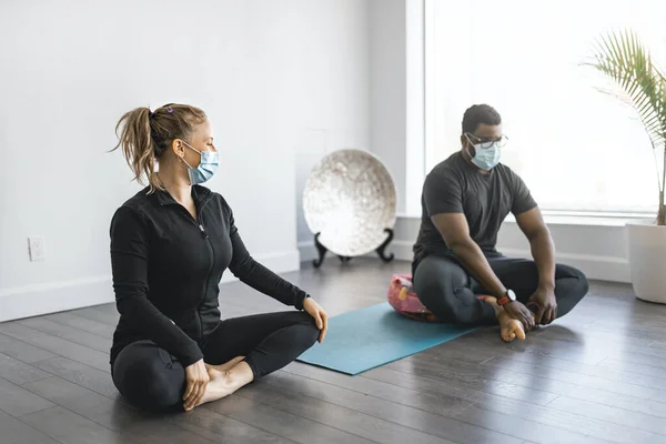 Персональний тренер займається позуванням йоги в сонячній студії з клієнтською маскою — стокове фото