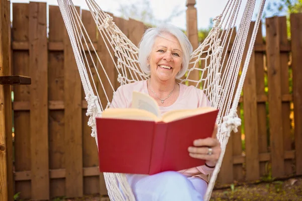 The senior woman with a book in a hammock — стоковое фото