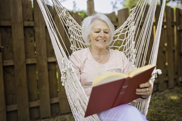 The senior woman with a book in a hammock — стоковое фото
