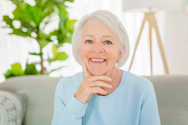 Yaşlı bir kadının portresi evdeki kanepede oturuyor. — Stok fotoğraf