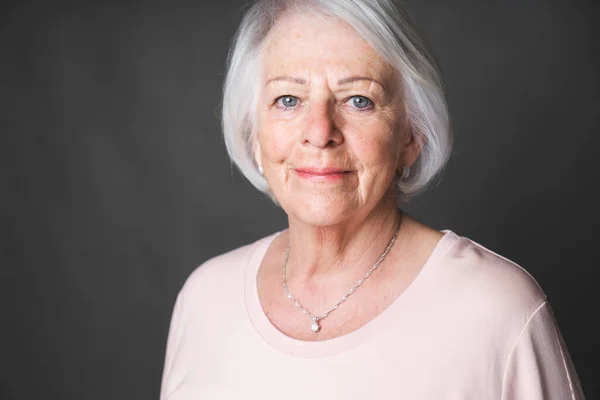 Nice portrait of a retired senior woman on studio background — Stock Photo, Image