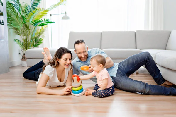 幸せな母親と父親と赤ちゃんの娘が家で遊んでいます — ストック写真