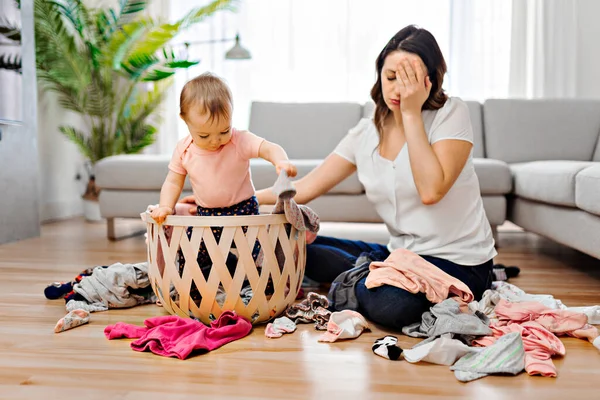 woman have problem choosing clothes with baby in the living room