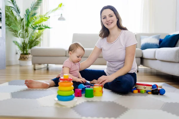 Kvinna leker med sitt barn i vardagsrummet — Stockfoto