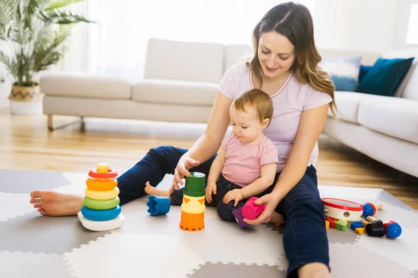 Kvinna leker med sitt barn i vardagsrummet — Stockfoto