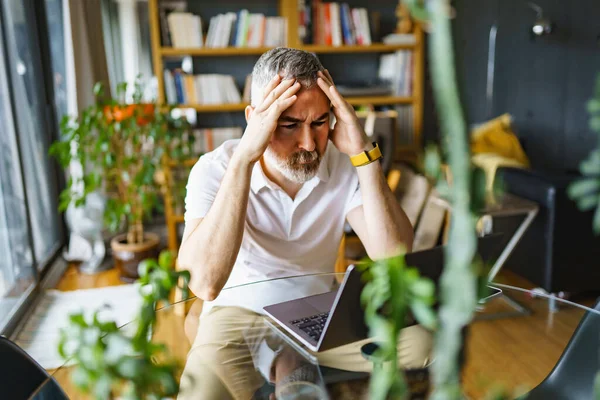 Businessman sitting at desk in bright office using laptop with sad attitude — Foto de Stock