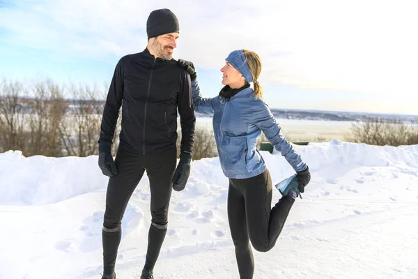 Mature couple stretching leg outside in winter season — Stockfoto