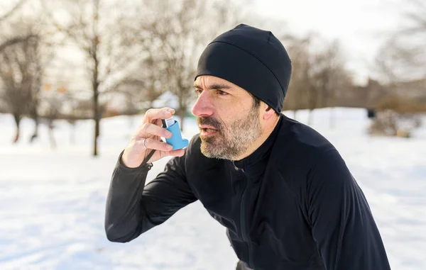 Mature man running at winter in park have some breathing difficulties and using asthma pump —  Fotos de Stock