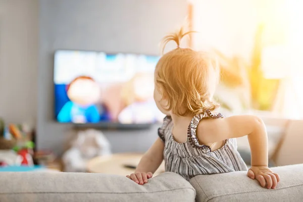 Cute little girl from back watching tv at home — Fotografia de Stock