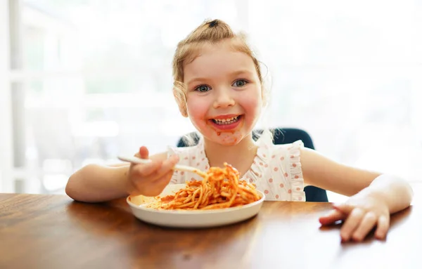 Hungry little girl eating spaghetti at home kitchen — Stockfoto