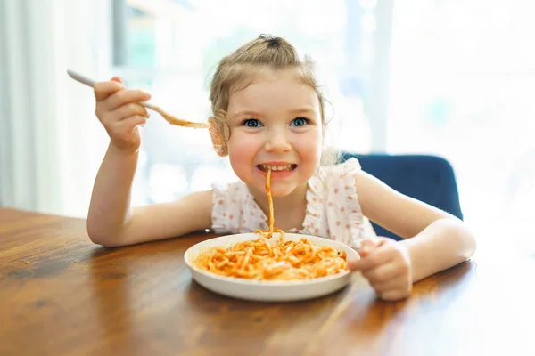 Hongerig klein meisje eten spaghetti thuis keuken — Stockfoto