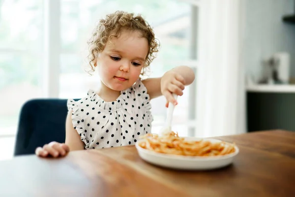 Hongerig klein meisje eten spaghetti thuis keuken — Stockfoto