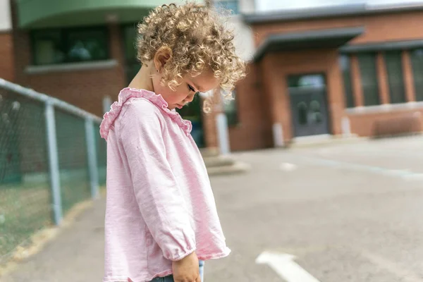 Young girl sitting on the floor at the school playground — Stock Photo, Image