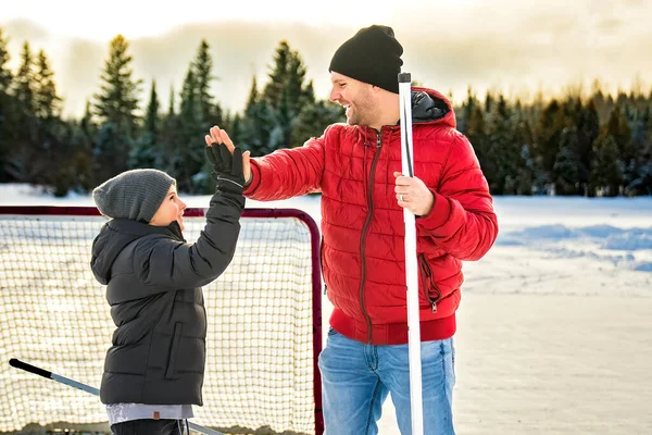 Father and son playing hockey together outside on a lake — Fotografia de Stock