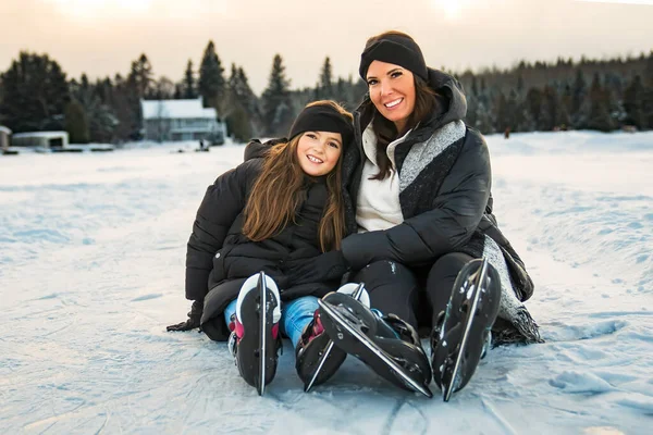 Mother and daughter ice skating outside on lake — Stock fotografie