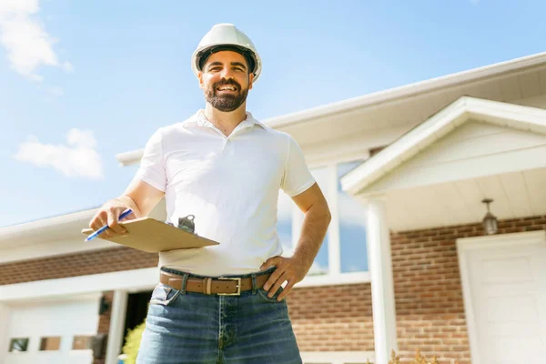 man with a white hard hat holding a clipboard, inspect house