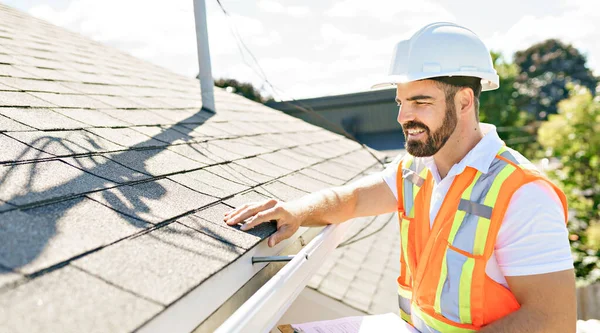 man in a hard hat, holding a clipboard, standing on the steps of an old rundown house.