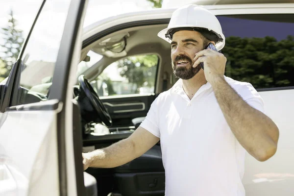 Man engineer builder wearing a white hard hat, shirt in front of his pickup using cellphone and seem to be unhappy about something — Stockfoto