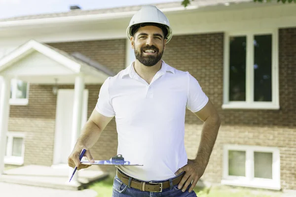 Mann mit weißem Hut hält Klemmbrett in der Hand, inspiziert Haus — Stockfoto