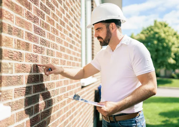 Hombre con un sombrero duro blanco sosteniendo un portapapeles, inspeccionar la casa —  Fotos de Stock