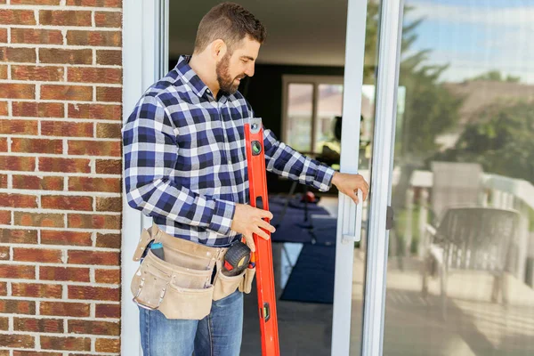 Handsome young man installing bay window in a new house construction site with level —  Fotos de Stock