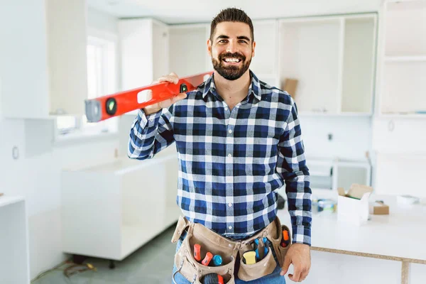 Concentrated young man work with white cabinet in the kitchen with level — Stockfoto