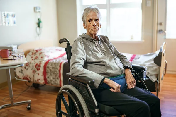 Sick, elderly senior woman in a hospital room with wheel chair — Stock Photo, Image